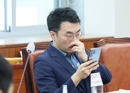 '거액 코인보유·이상거래 의혹'으로 더불어민주당을 탈당한 무소속 김남국 의원이 지난 8월25일 국회 교육위원회 전체회의에 참석한 가운데 자신의 휴대전화를 들여다 보고 있다.<연합뉴스>